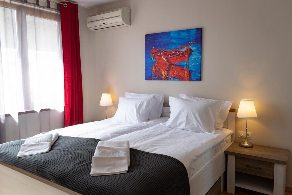 a bedroom with a large white bed and a painting on the wall at STUDIO 3 in Varna City