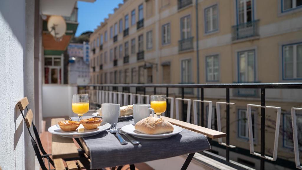 a table with food and glasses of orange juice on a balcony at The Mouraria Apartment in Lisbon