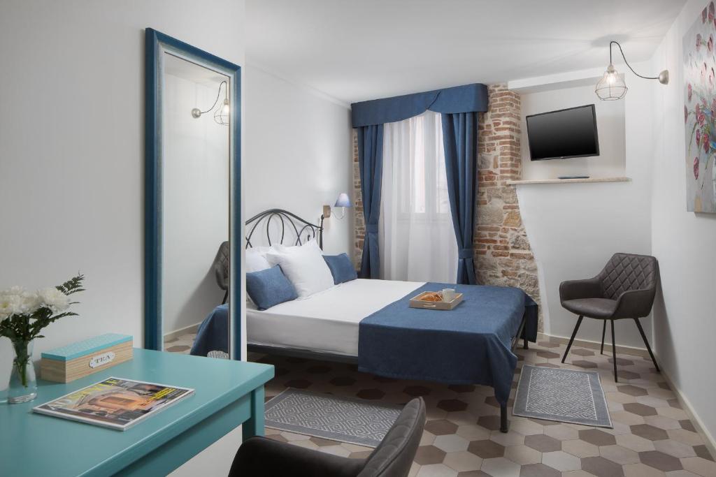 a hotel room with a bed and a table and a desk at Noemi's rooms in Rovinj