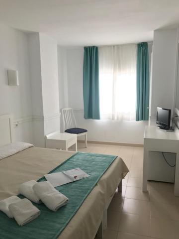 a bedroom with a bed with a green blanket at Hostal Brisa Marina in Port d'Alcudia