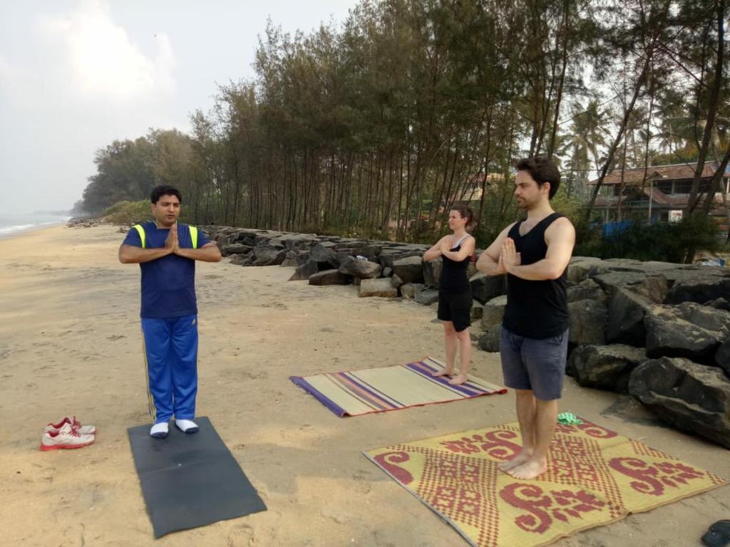 three men standing on a yoga mat on the beach at Cherai Ocean View Home in Cherai Beach