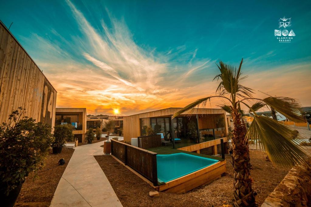 una casa con una piscina y una palmera en Noa Glamping Resort, en Novalja