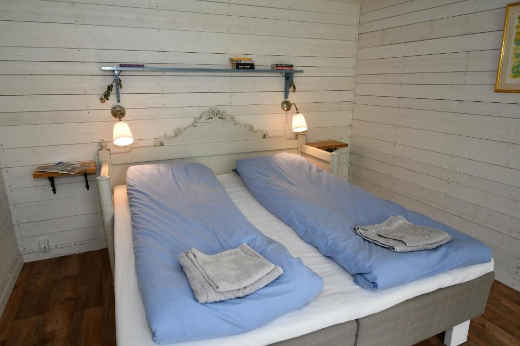 ein Bett mit blauer Bettwäsche und zwei Handtüchern darauf in der Unterkunft Kolarbogård in Fors