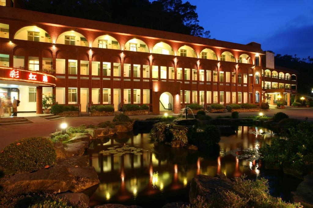 un grande edificio con un laghetto di fronte di Rainbow Resort Hotel a Wenquan