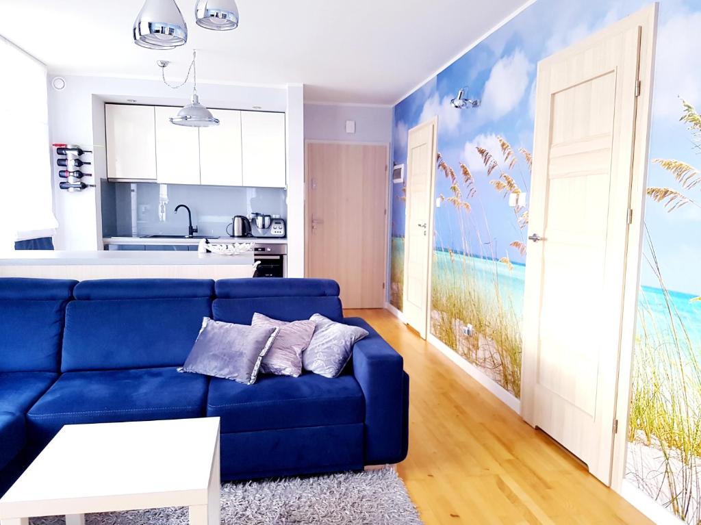 ein Wohnzimmer mit einem blauen Sofa und einer Küche in der Unterkunft ApartMorze apartamenty Fregata in Jastrzębia Góra