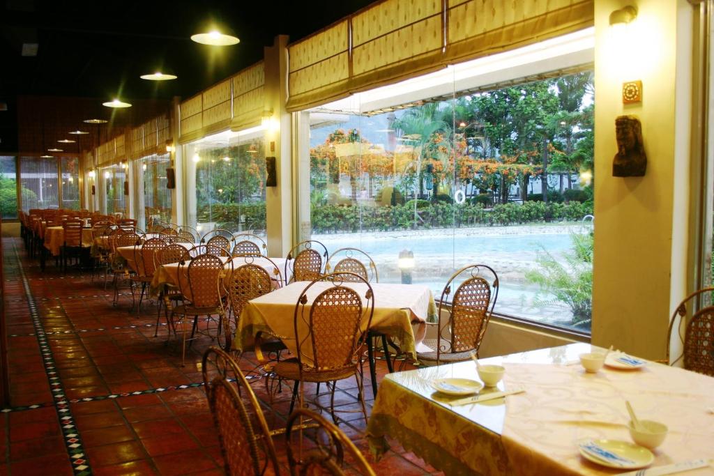 an empty restaurant with tables and chairs and a window at Rainbow Resort Hotel in Wenquan