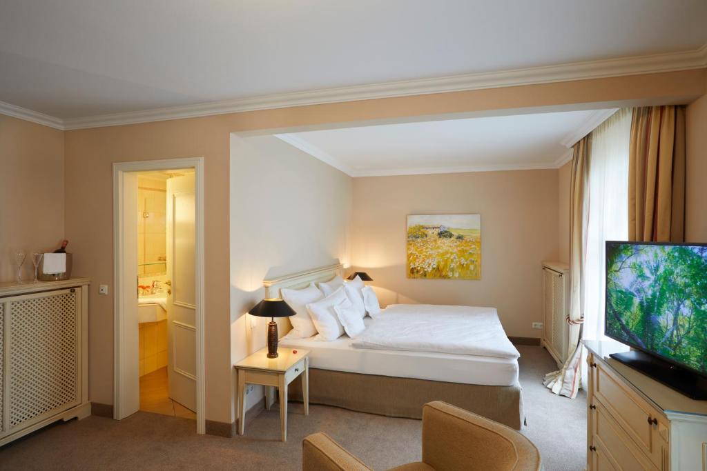 a bedroom with a bed and a flat screen tv at Strandhotel Fontana in Timmendorfer Strand