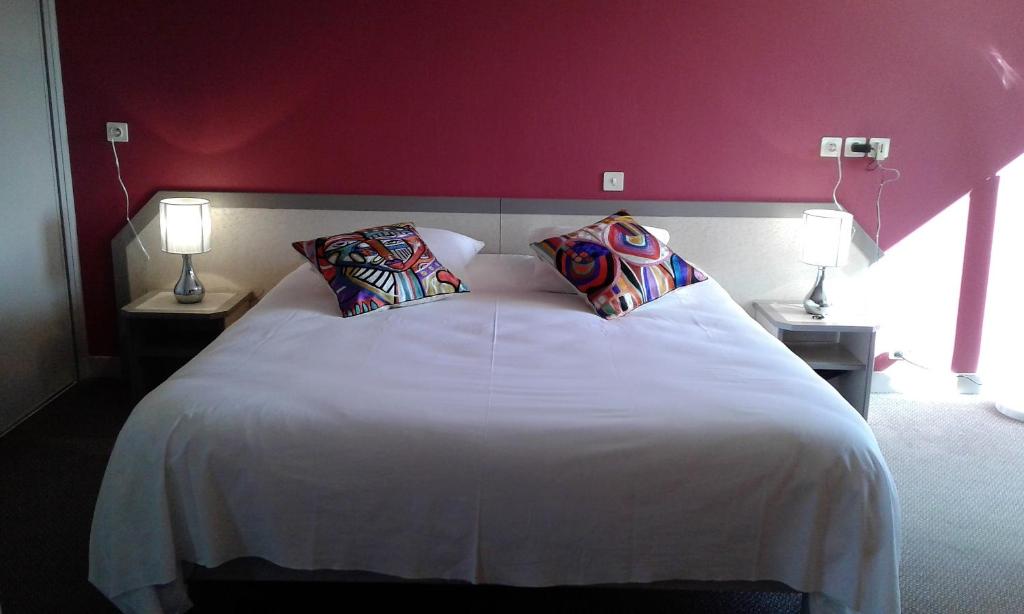 una camera da letto con un grande letto bianco con due lampade di Hotel Restaurant Le Capricorne a Pouldreuzic