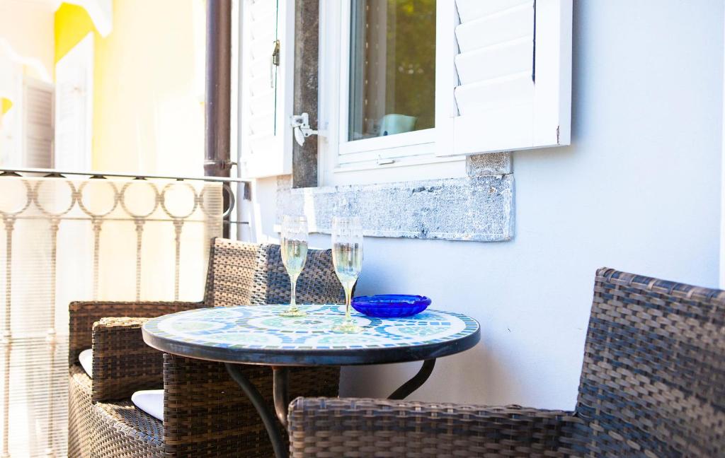 stół z 2 kieliszkami do wina na balkonie w obiekcie Apartments Delić w mieście Ika