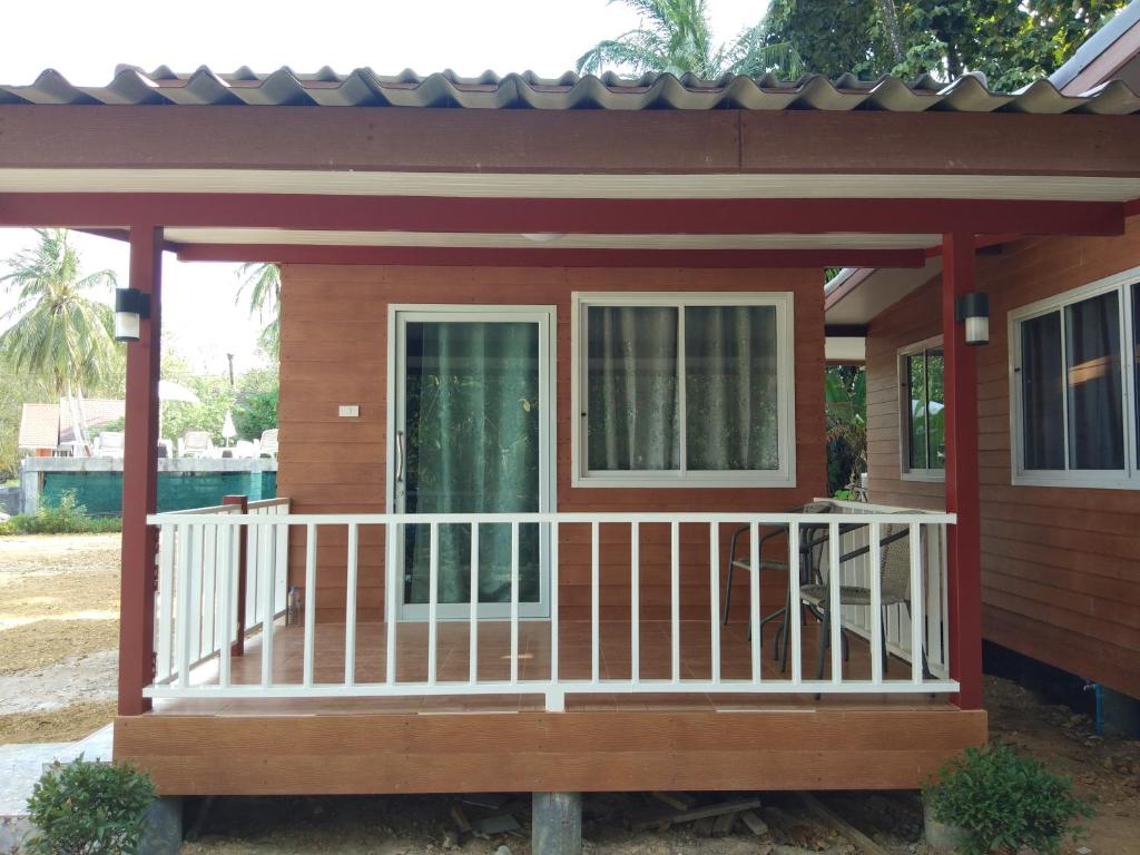 Cette petite maison dispose d'une terrasse couverte et d'une balustrade blanche. dans l'établissement Mook Paradise Bungalow, à Ko Muk