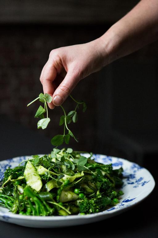 a person holding a plant leaf above a plate of greens at Whitehouse Rye in Rye