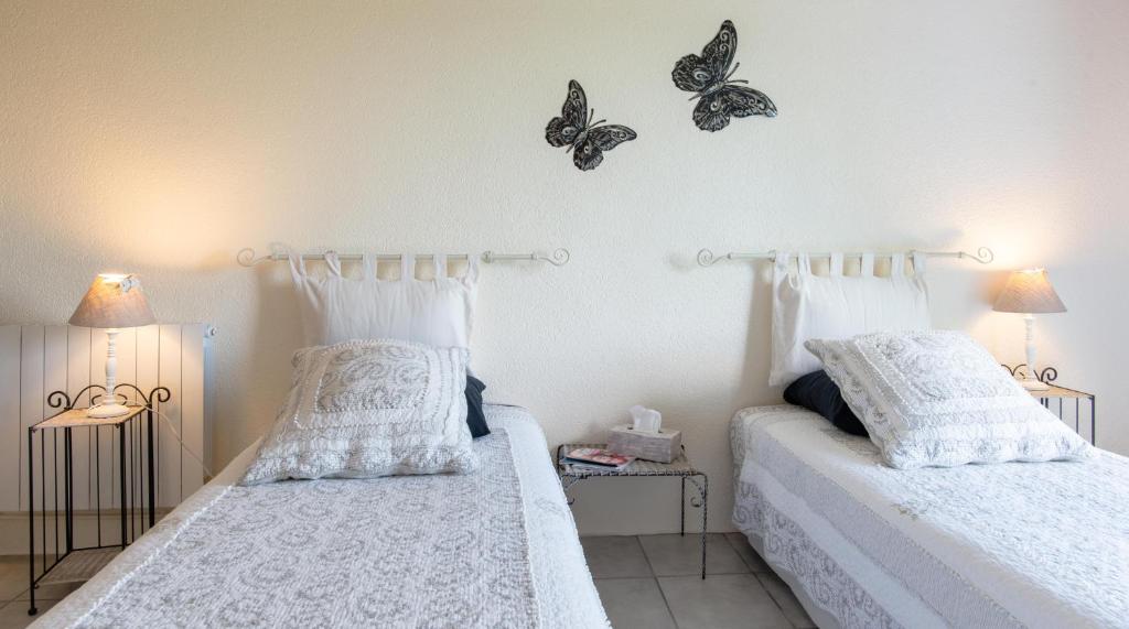 two beds in a bedroom with butterflies on the wall at Chambres d'hôtes Larroquinière in Port-Sainte-Marie