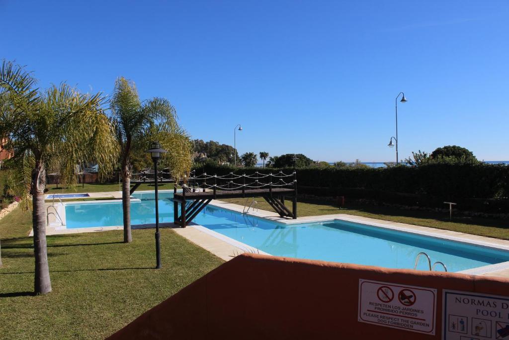 een zwembad in een park met een palmboom bij PLAYA ANGEL in Estepona