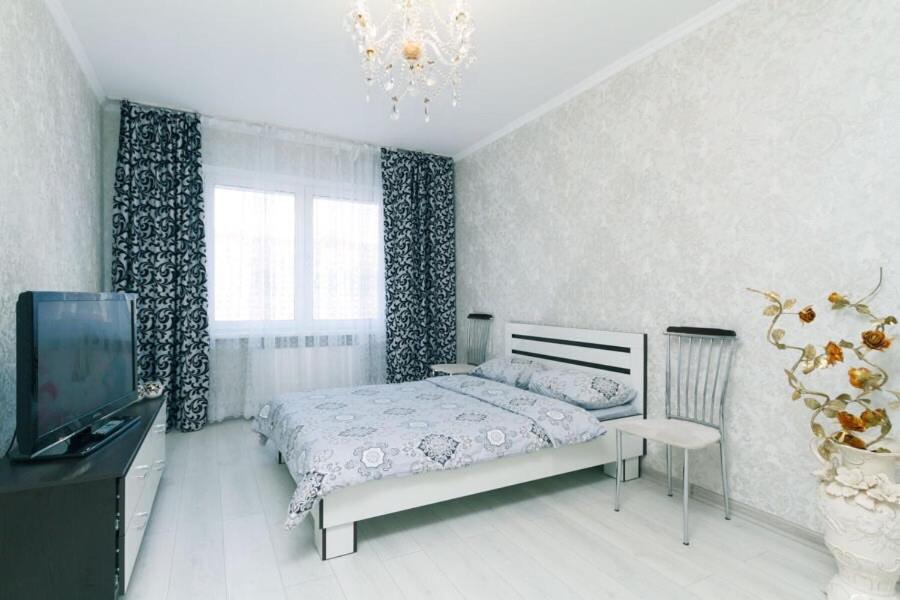 sypialnia z łóżkiem, telewizorem i żyrandolem w obiekcie 1 вулиця Софії Русової w Kijowie
