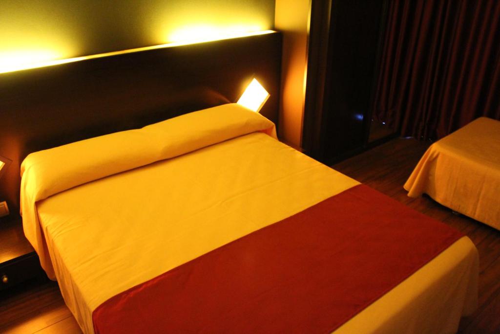 a bed in a hotel room with a red white and red at Hostal Royal Almorox in Almorox