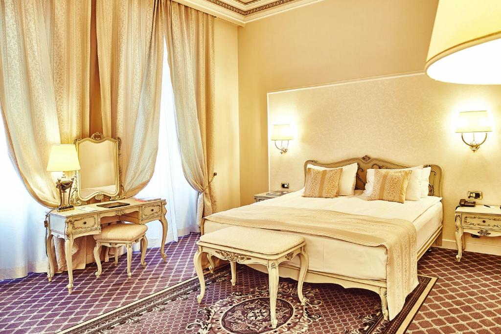 a bedroom with a bed and two tables and a mirror at Grand Hotel Continental Bucuresti in Bucharest