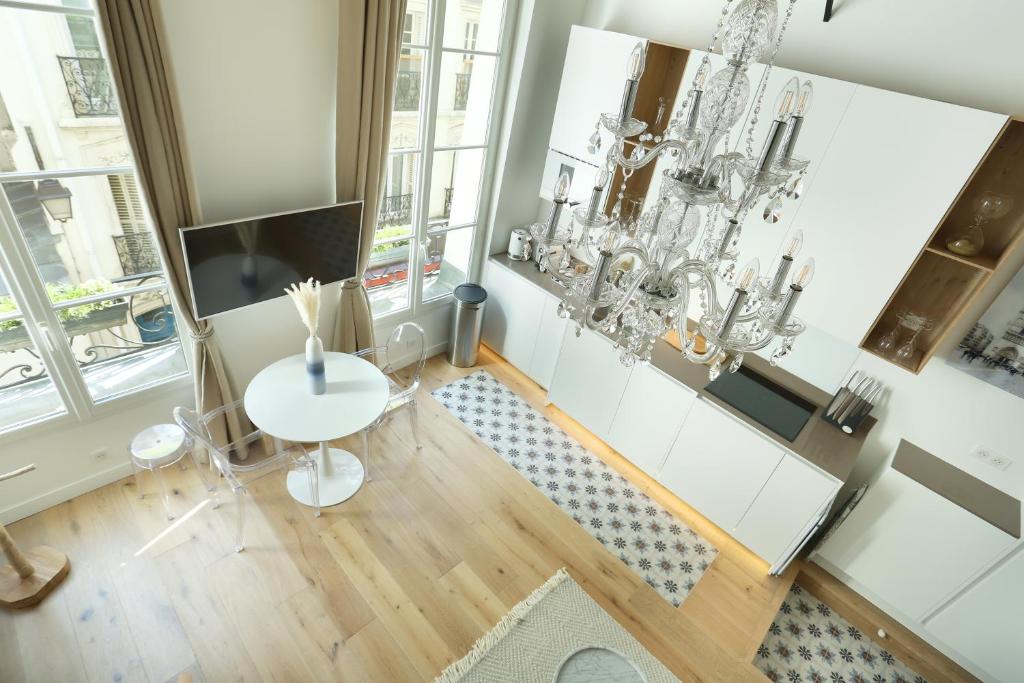 a living room with a white table and chandelier at Résidence Le Marais by Studio prestige in Paris