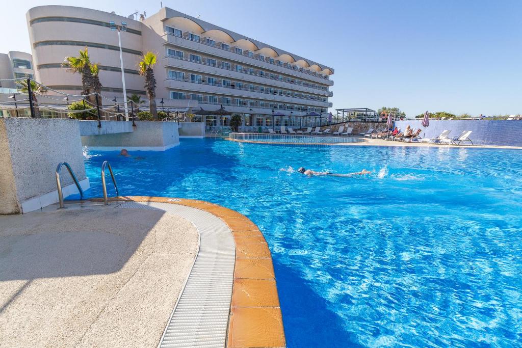 a swimming pool in front of a large building at Eix Platja Daurada Hotel & SPA in Can Picafort