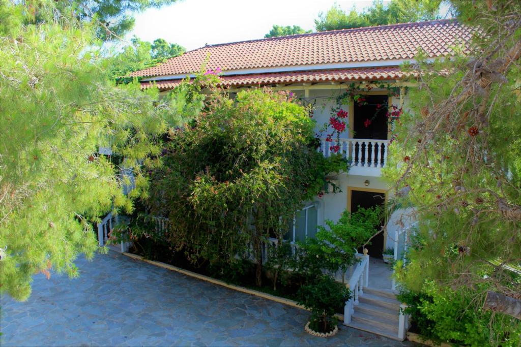 une maison blanche avec un portail et des arbres dans l'établissement Pavlos studios, à Laganas