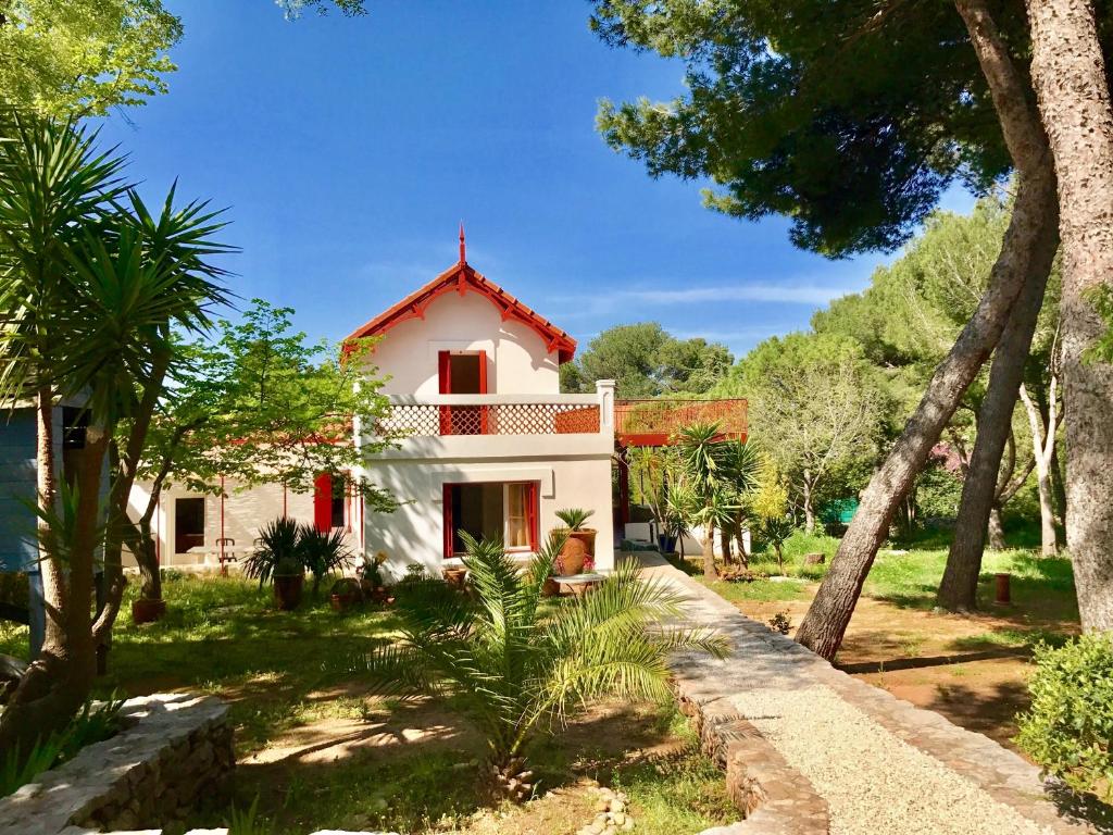 a white house with red windows and trees at Villa de Charme sur la Corniche in Sète