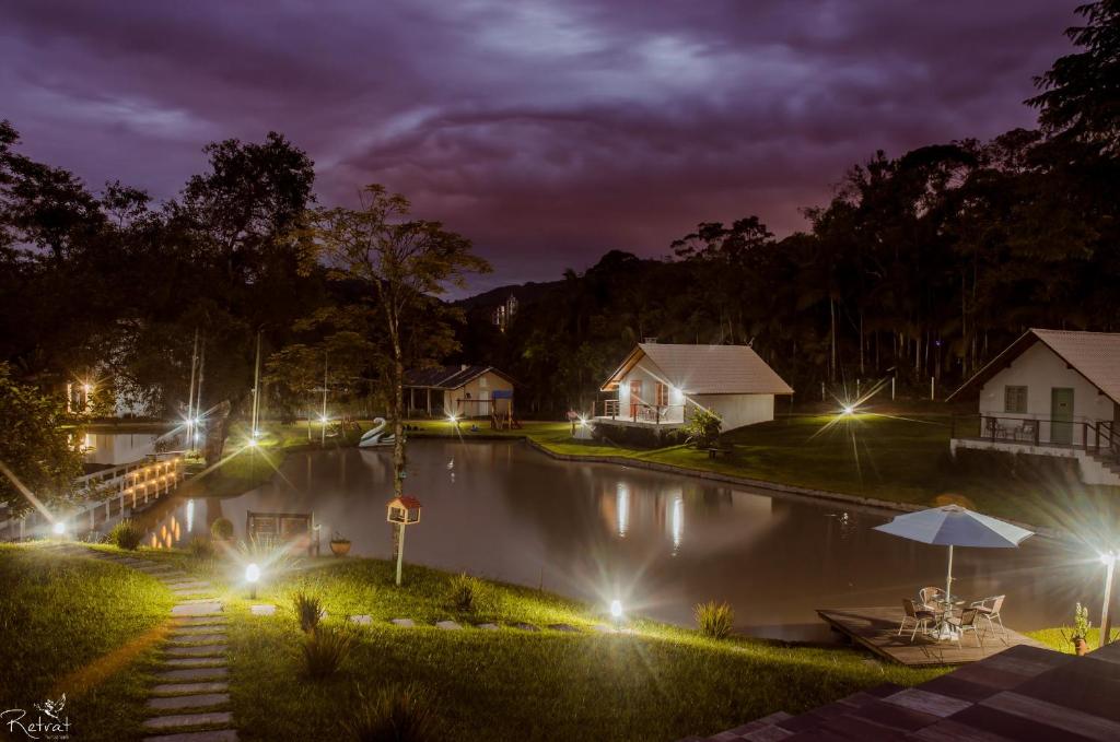 uma foto noturna de uma casa com luzes na água em Chalés Pomerode em Pomerode