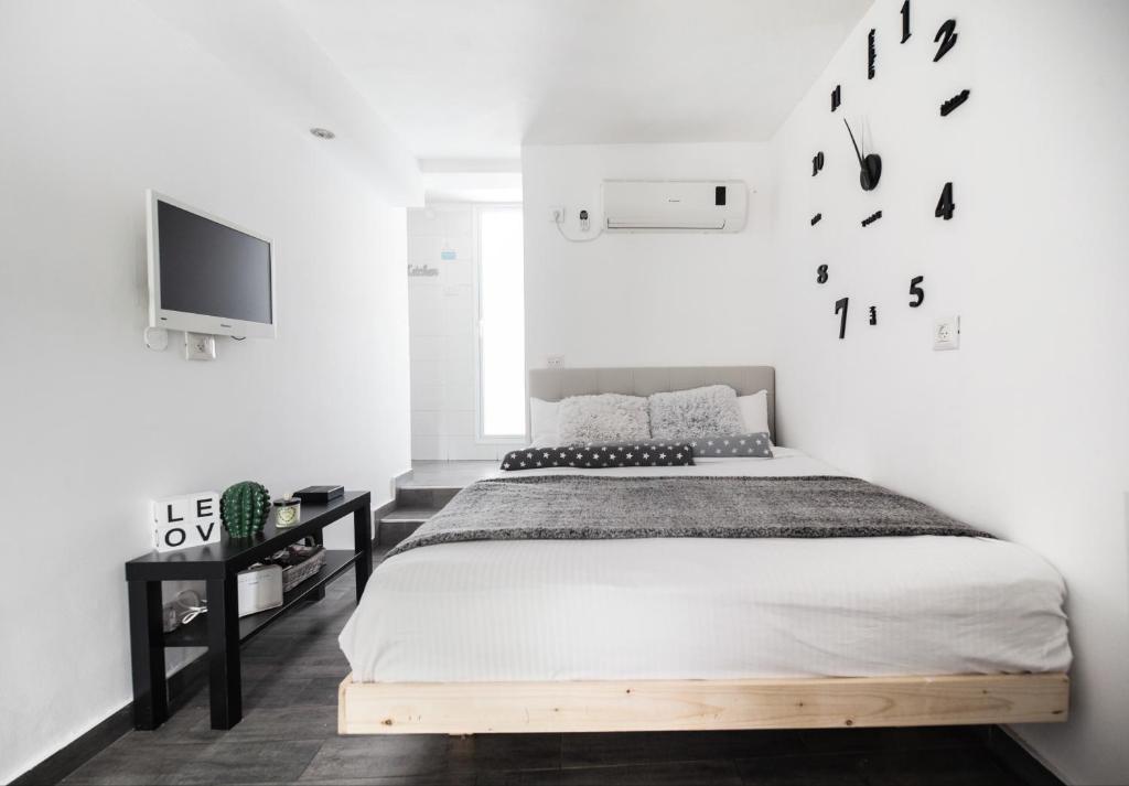 1 dormitorio con 1 cama y TV en la pared en Stunning Studio By The Beach With Free Parking, en Tel Aviv
