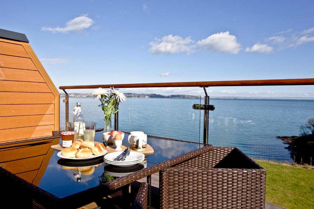a table on a balcony with a view of the water at Avocet 2 at The Cove - Stunning Sea Views, Heated Pool and Parking in Brixham