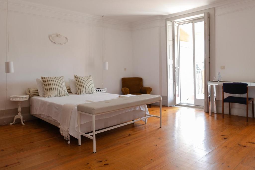 a white bedroom with a bed and a wooden floor at Pensao Favorita in Porto