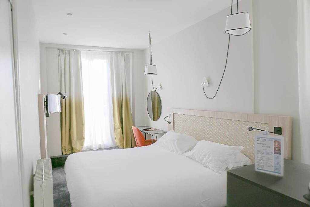 a bedroom with a white bed and a window at Hôtel Vendôme in Nice