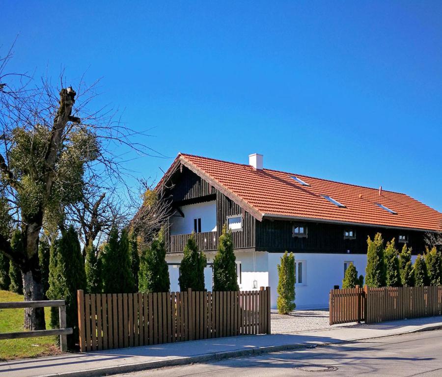 a white house with a red roof and a fence at Münsing Nähe Starnberger See, schöne Ferienwohnung, Gästewohnung 125qm EG und OG KONTAKTFREI in Münsing