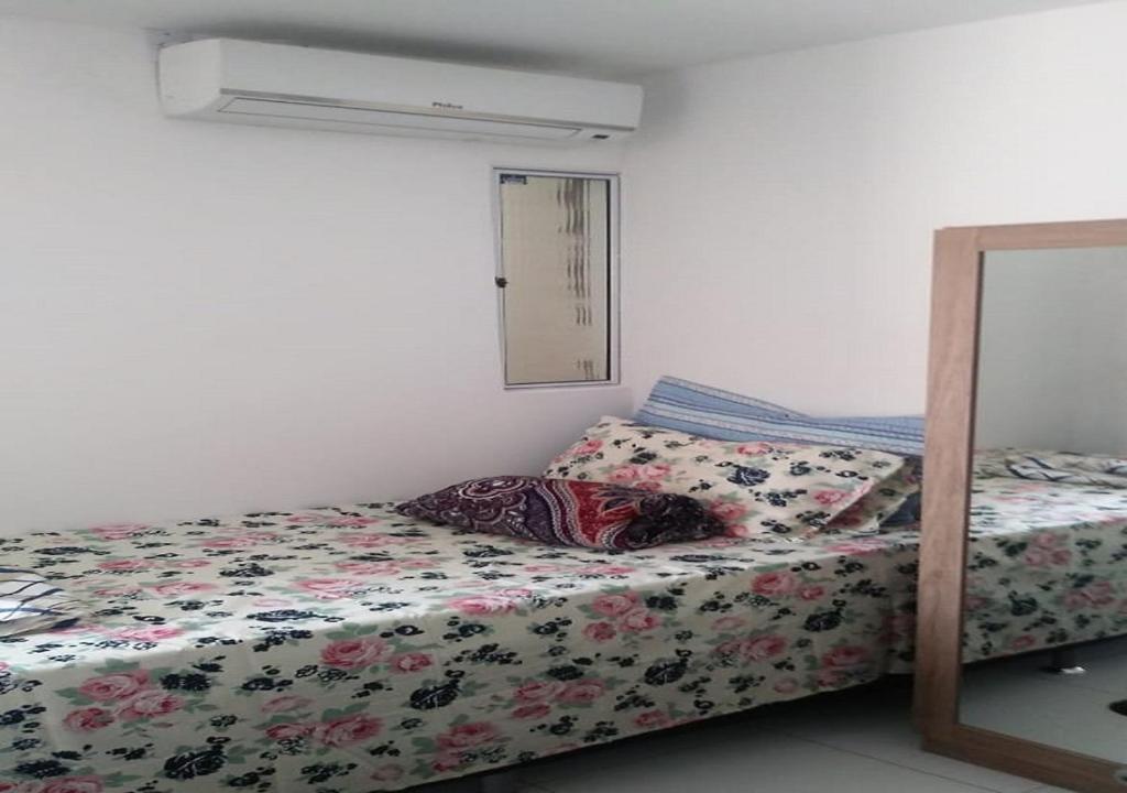 a bedroom with a bed with a floral comforter at Residencial Dom Laurindo in Paulo Afonso