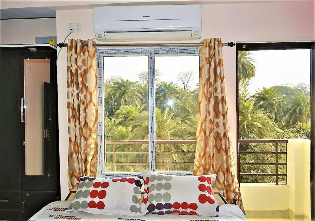 a bedroom with a bed and a large window at Pretty Garden View Apartment 3BHK Furnished Flat near Kashi Vishwanath Temple in Varanasi