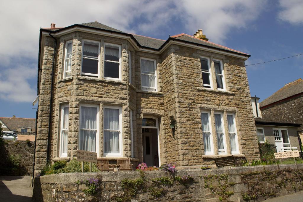 a stone house with white windows on a street at Glenleigh Bed and Breakfast in Marazion