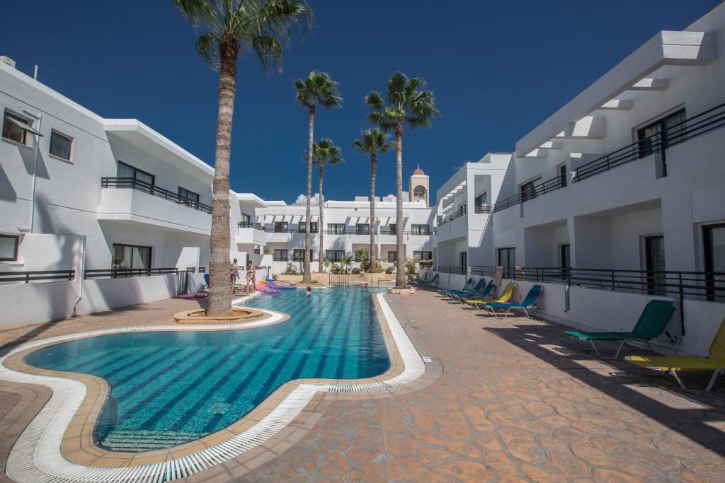 a swimming pool next to a building with palm trees at Anthea Hotel Apartments in Ayia Napa