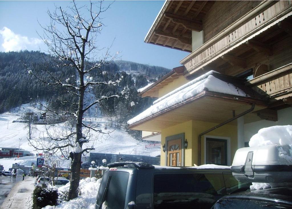 un'auto parcheggiata di fronte a un edificio nella neve di Hotel Garni Klocker a Kaltenbach