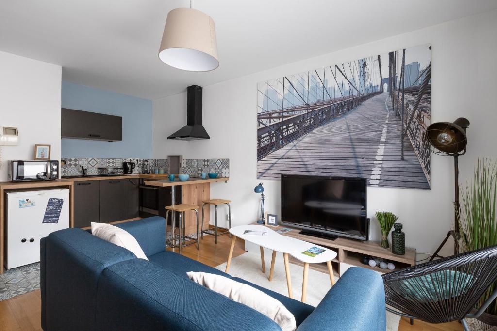 un salon avec un canapé bleu et une cuisine dans l'établissement Nelson by Cocoonr, à Nantes