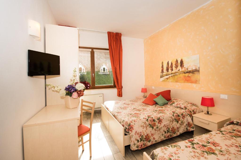 1 dormitorio con 1 cama y escritorio con TV en Bed & Breakfast Camollia en Siena