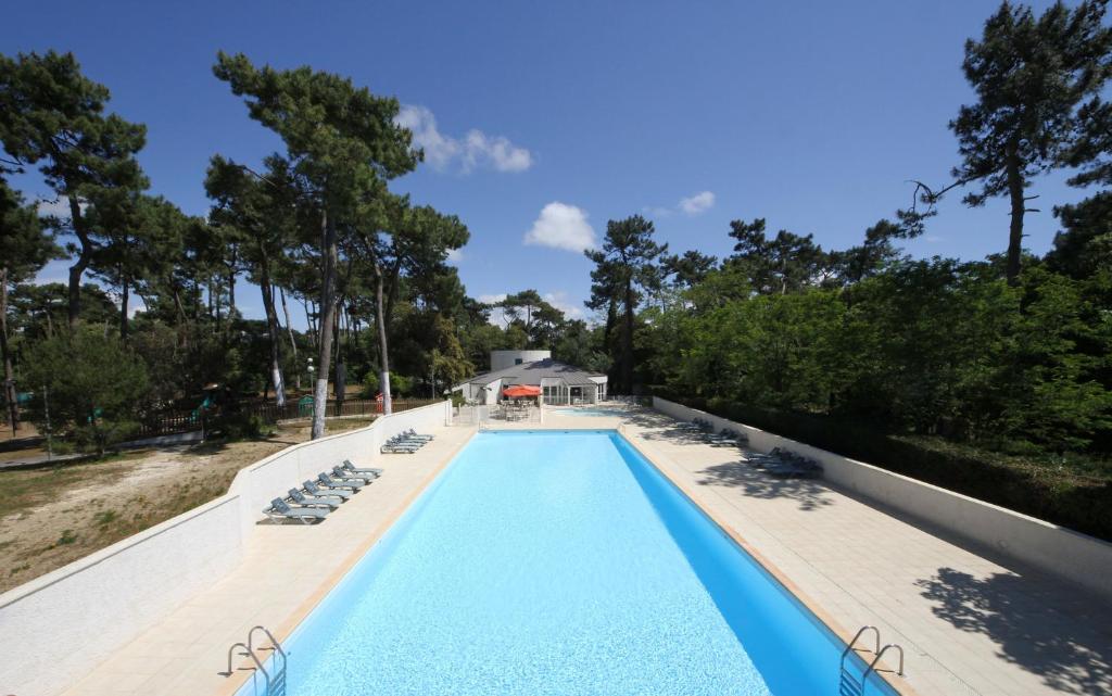 une piscine avec des chaises longues et une maison dans l'établissement Arc en Ciel Oléron, à Saint-Trojan-les-Bains