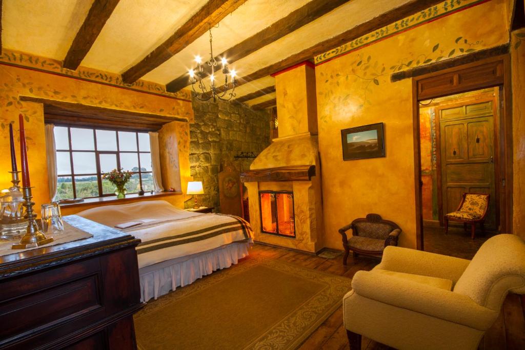 1 dormitorio con 1 cama, chimenea y silla en Hacienda San Agustin de Callo en Lasso