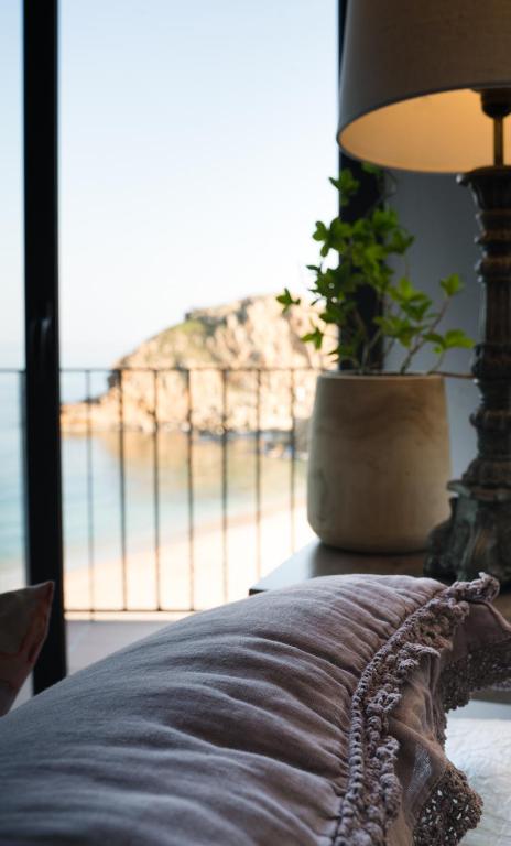 a bed with a lamp and a view of a beach at Hostal Sa Malica in Blanes