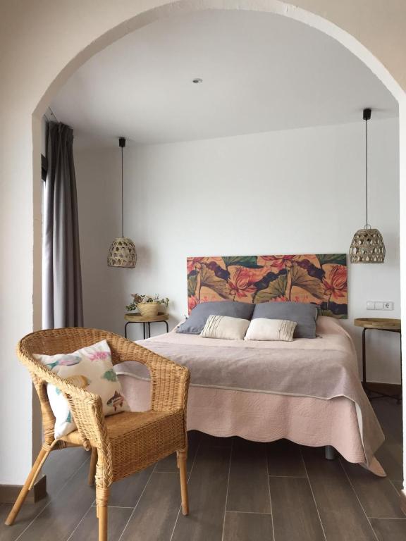 a bedroom with a large bed and a chair at Hostal Sa Malica in Blanes