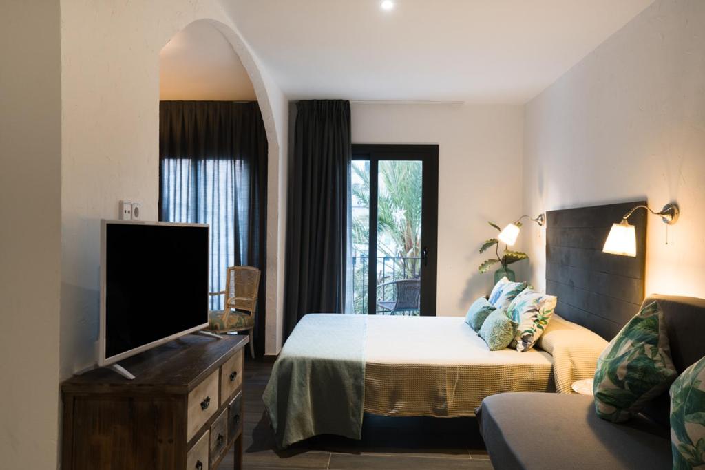 a bedroom with a bed and a tv and a couch at Hostal Sa Malica in Blanes