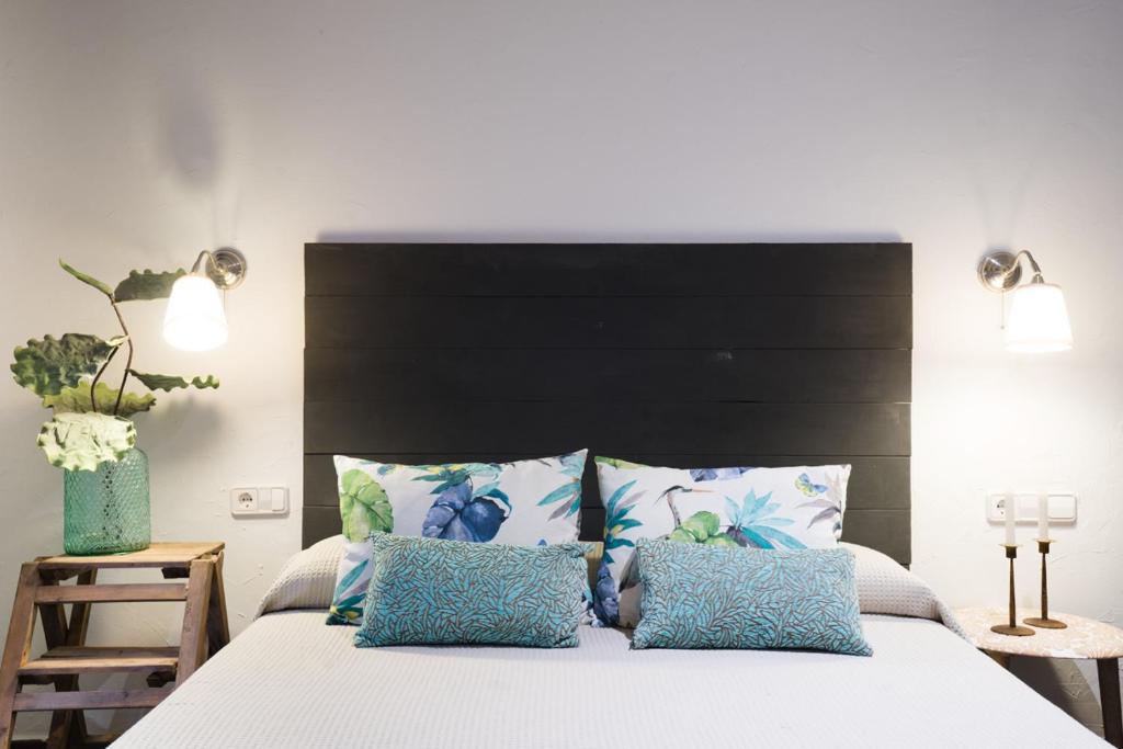 a bedroom with a bed with a black headboard and blue pillows at Hostal Sa Malica in Blanes