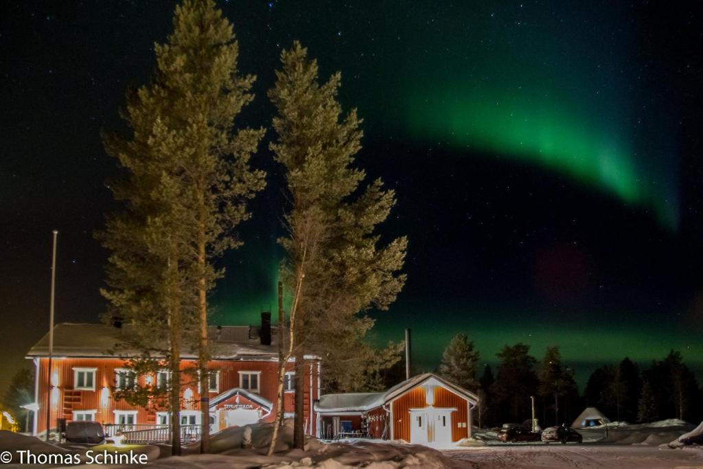 an aurora shines in the sky over a house at Vuotson Maja B&B in Vuotso