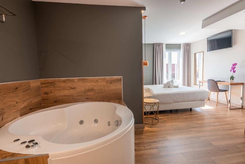 a large bath tub in a room with a bedroom at Hotel Gastronómico Torre de Galizano in Galizano