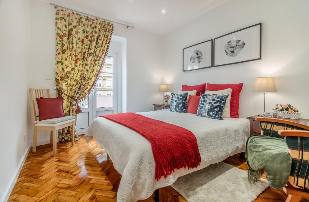 Schlafzimmer mit einem Bett mit roten und blauen Kissen in der Unterkunft Lisbon Stay at Roma Boulevard in Lissabon