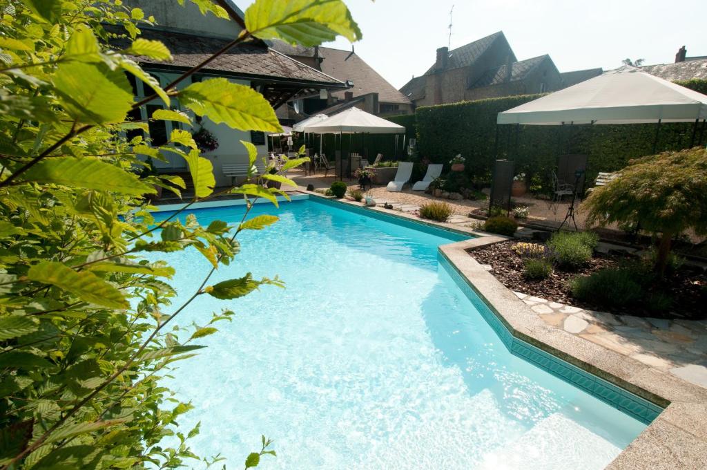a swimming pool with blue water in a yard at Hotel Nougier in Saint-Étienne-de-Fursac