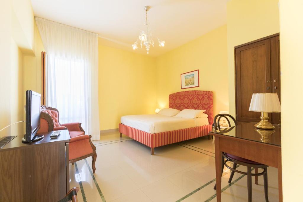 a bedroom with a bed and a desk and a television at Masseria Sant'Anna in Bari