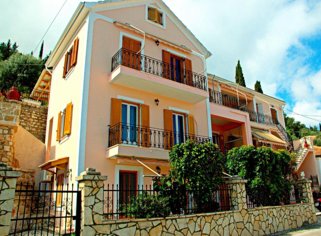 a white house with balconies on a stone wall at Korona Apartments in Vathi