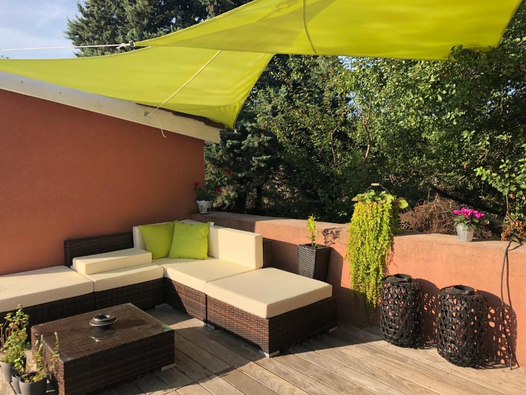 a patio with a couch and a yellow umbrella at Communay Gablys Chambres in Communay